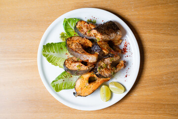 Baked fish with herbs and lemon. Seafood on white plate top view.