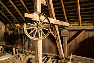 An old wagon wheel and numerous leather harnes straps inside an old abandoned barn near Jefferson Oregon. - obrazy, fototapety, plakaty