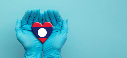 Doctors hands wearing surgical gloves holding Laos flag heart
