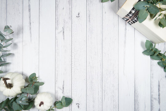 Decorated border background. On-trend farmhouse aesthetic flatlay flatlay with farmhouse style decor, stack of books, and bows on a white wood background. Negative copy space.