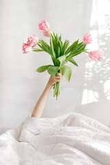 good morning pink tulips in a woman's hand in bed, birthday greetings, international women's day, valentine's day, gift, flowers, pink bouquet, spring tulips, surprise