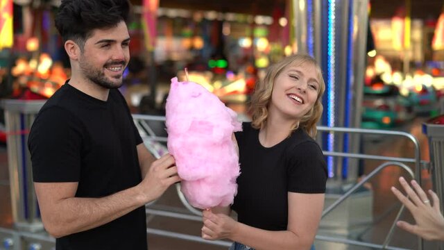Pareja de chico moreno y chica rubia guapa compartiendo algod&oacute;n de az&uacute;car rosa