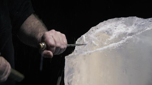 Carving of the ice, artist is using a chisel and hammer to break off ice, 4k