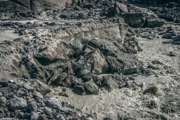 Scenic landscape with powerful mountain river beginning from glacier with ice chunks. Beautiful scenery with glacier at source of turbulent glacial river. Mountain river among moraines and ice blocks.