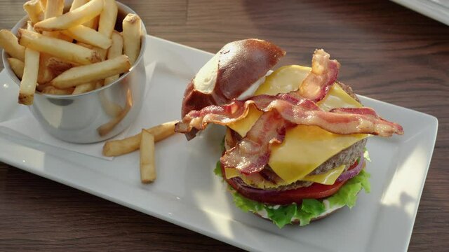 Double Cheese Burger with bacon and French Fries camera orbits over plate