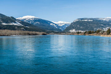 wide Columbia river with snow in mountains blue sky early spring British Columbia Canada