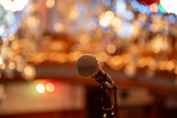 A silver metal microphone on a stand. The round ball style mic is a classic for concerts and...