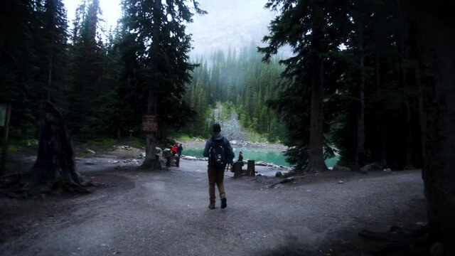 Young guy walking toward misty lake in slow motion.