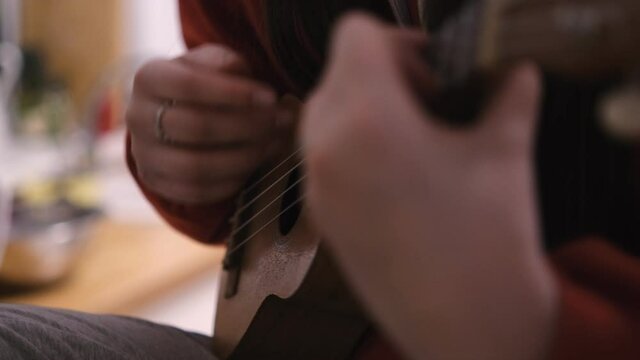 Hands of young pretty girl playing on brown ukulele 4K