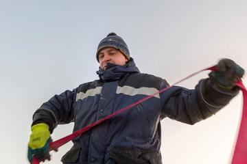 A portrait of an installer in a blue jacket with a ribbon rag sling