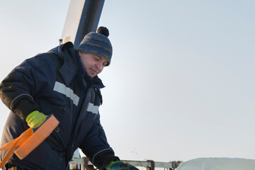 A portrait of an installer in a blue jacket with a ribbon rag sling