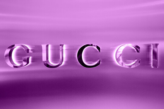 Gucci boutique exterior sign, italian luxury brand of fashion goods and leather goods. Illuminated Gucci logo of apparel store showcase. Fashion district in Milan. Milan, Italy - 15.12.2020