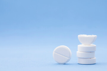 Pharmaceutical medical set of white pills stacked in the form of a tower on a blue background with copy space. Prescription medicine, antibiotic concept in round tablets with space for text close up.