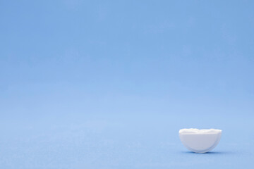 Pharmaceutical, medical part of metered white pill broken in half on blue background with copy space. Prescription medicine in volume or rate for patient, antibiotic concept with text space.