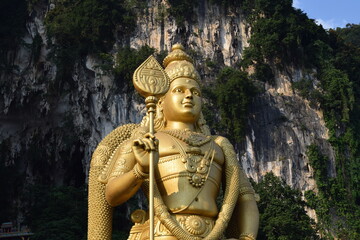 Golden statue of Lord Murugan Hindu deity in front of the Batu Caves 