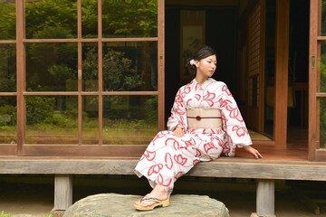 古民家の和室の縁側にてくつろぐ浴衣を着た若い女性