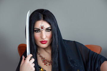 close up portrait of a beautiful young woman with black hair dressed in an oriental beauty costume...