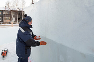 Fototapeta na wymiar Worker covers the joints of ice panels with wet snow