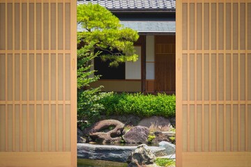 A traditional Japanese wooden door opens to a Japanese garden