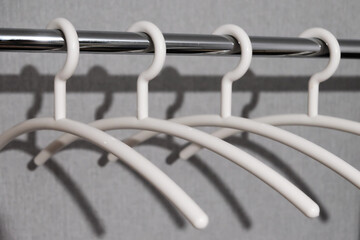 close-up of many white plastic clothes hanger on rod with shadow