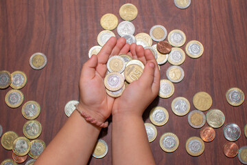 manos de niña de 3 años sujetando monedas de argentina 