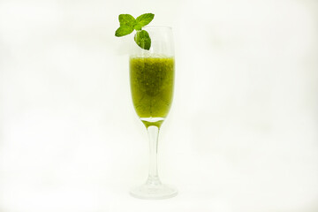 fluted glass cup containing fresh green juice with nopal spinach lemon juice pineapple and orange