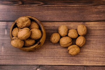 Bunch of walnuts lies in a wooden cup and on a wood background. High quality photo