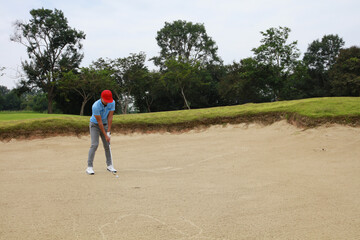 Fototapeta na wymiar Male golf palyer start hit the golf from sand, Golfers hit the ball in the sand. Speed and Strength