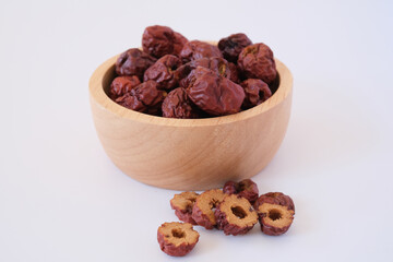 Red dates or red jujubes in wooden bowl isolated on white background. Selected focus.
