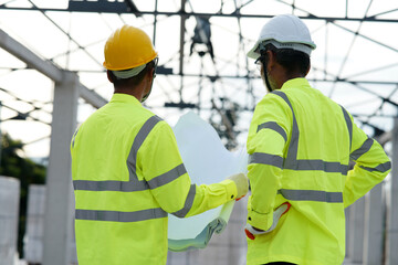 Construction concept of Engineer and Architect working at Construction Site with blue print Engineer technician Looking Up and Analyzing an Unfinished Construction Project.