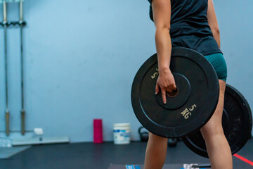 a woman in the gym doing crossfit holding a weight 5kg