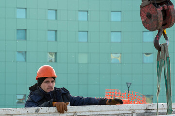 A portrait of a fitter in a blue jacket at the hook of a truck crane