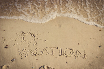 Inscription vacation with shape of sun and incoming sea wave on sand at beach. Summer time