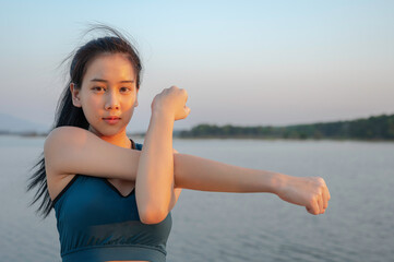 Fototapeta na wymiar Chanthaburi - Thailand 13 February 2021 : Young beautiful Asian woman in sports outfits doing stretching before workout outdoor in the park in the morning to get a healthy lifestyle. Healthy young wom