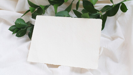 Photostock wedding styled composition. Feminine desktop mockup scene with rusuc leaves, silk ribbon, blank greeting card on creme textured fabric background. Flat lay, top view.
