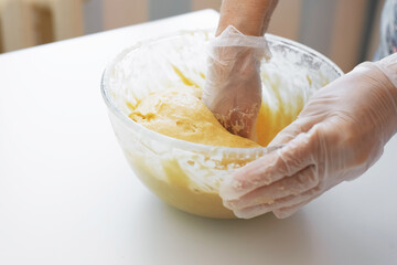 Woman preparing dough. Close-up of female hands in gloves whipping, kneading the dough.
