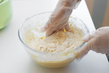 Female hands in gloves are kneading the dough, close-up. Cooking dough at home in the kitchen, selective focus