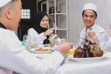 Fototapeta na wymiar Happy family gather and eat together at dining room during Eid Mubarak celebration