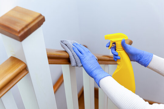 Woman hands in gloves cleaning stairs railings with rag