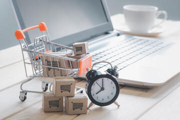 Boxes in a trolley shopping cart and clock with laptop keyboard. online shopping Idea,shopping at...