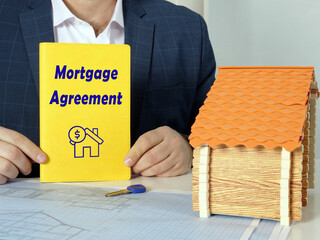 yellow notepad in a hand with phrase Mortgage Agreement . Horizontal shot. Close-up