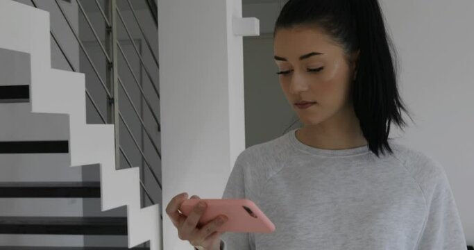 young woman in her house watching something on her smartphone