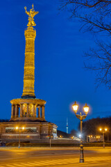 Fototapeta na wymiar The famous Victory Column with a street light and tree branches in Berlin, Germany, at night