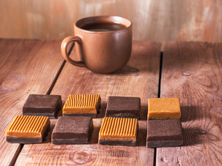 Morning tea in a brown ceramic mug and dessert with two colors toffee candy