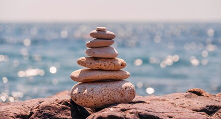 Pyramid stones on the seashore on a sunny day on the blue sea background. Happy holidays. Pebble beach, calm sea, travel destination. Concept of happy vacation on the sea, meditation, spa, calmness.