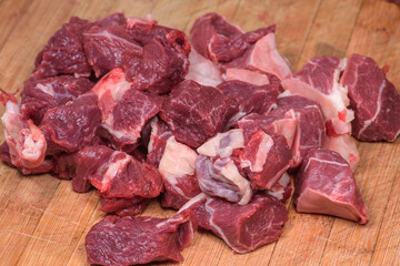 Cuttings of raw beef cut with a knife are placed on a chopping board, ready to cook.