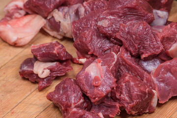 Cuttings of raw beef cut with a knife are placed on a chopping board, ready to cook.