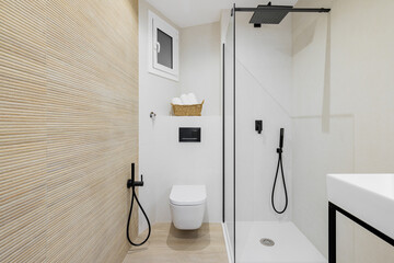 Interior of modern style bathroom in white and beige colors in refurbished apartment. Shower zone...