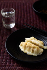 Close up of steamed wonton dumpling on black dish, Asian food