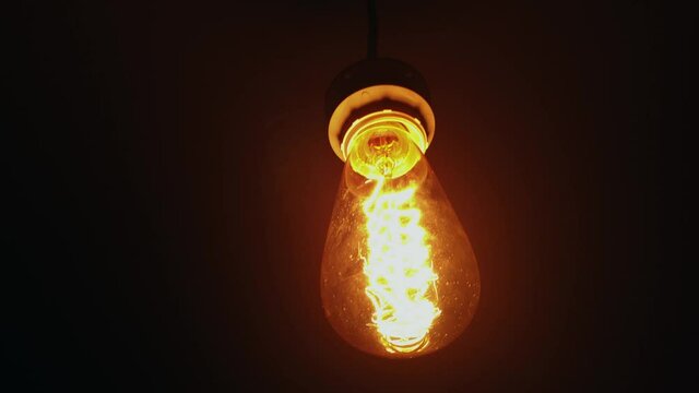 Squirrel cage incandescent light bulb hanging in the dark